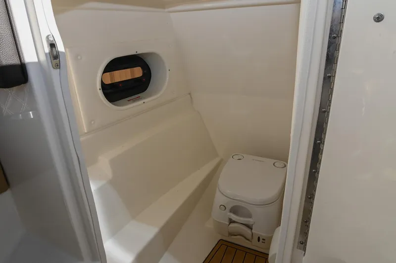 Slide: The Image of 2020 Sea Ray SLX 250 boat interior with compact marine toilet and window. - 26