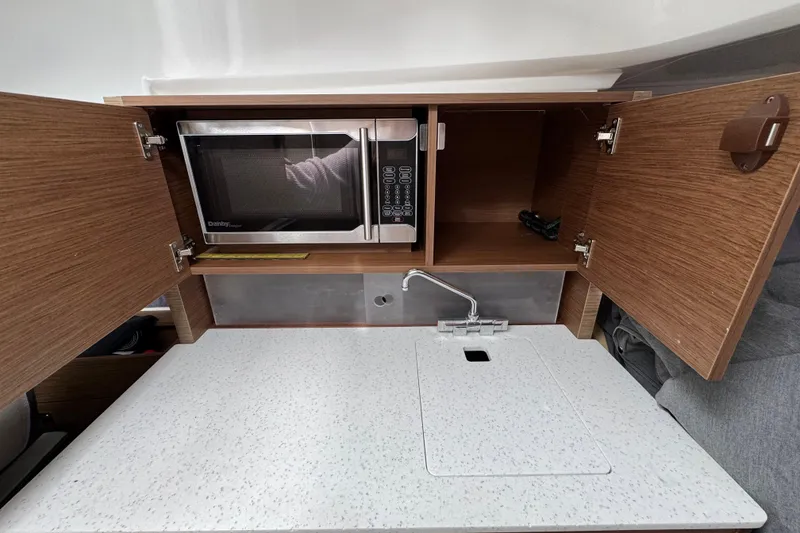 Slide: The Image of 2021 Jeanneau Leader 9.0 WA boat kitchenette with microwave, sink, and storage cabinets. - 17
