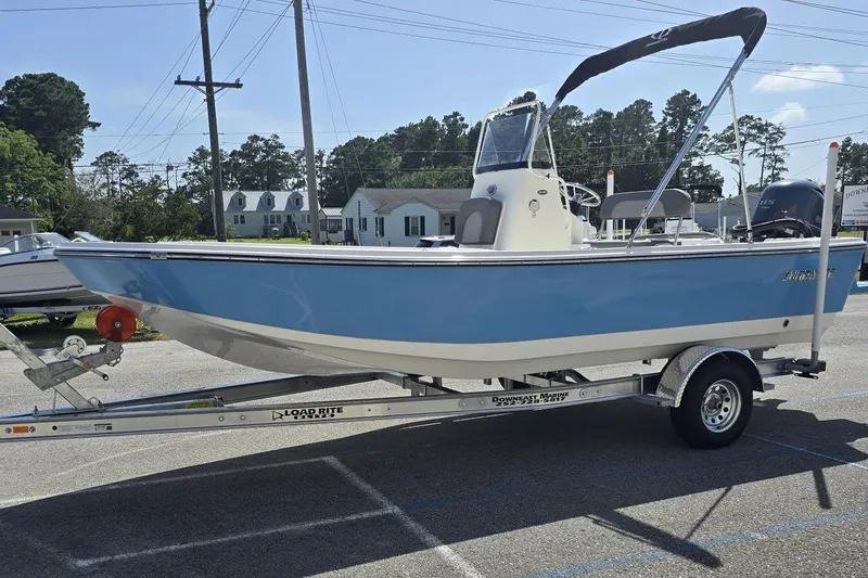 Slide: The Image of 2026 Sundance DX20 boat on trailer, blue and white design, parked outdoors. - 15