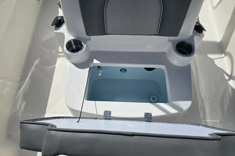 Slide: The Image of 2026 Sundance DX20 boat interior with open storage compartment and cup holders. - 9