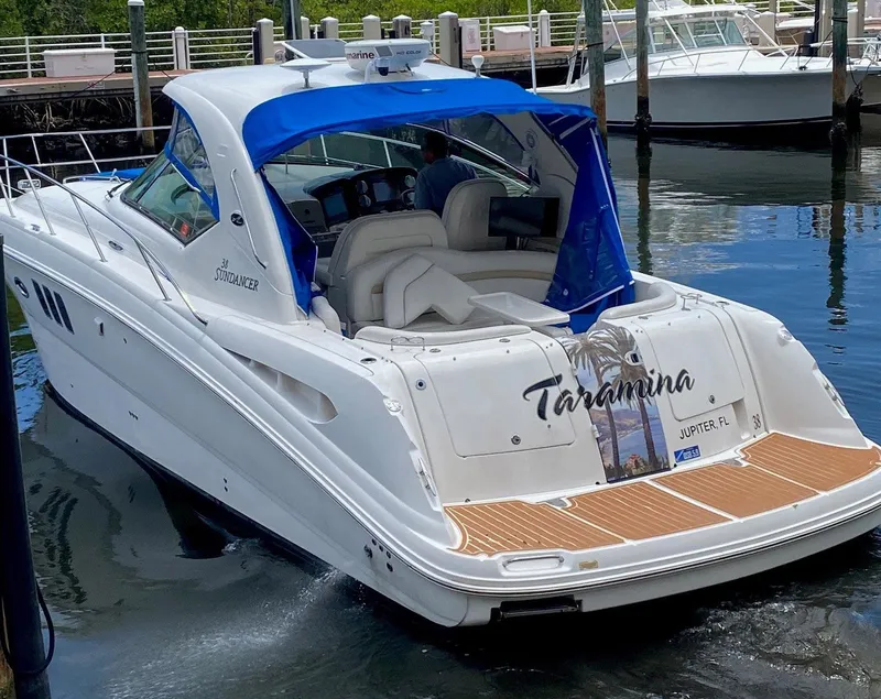 Slide: The Image of 2008 Sea Ray 38 Sundancer boat docked, featuring a blue canopy and teak swim platform. - 2