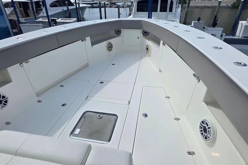 Slide: The Image of 2020 SeaVee 390Z boat deck with storage compartments and speakers at a marina. - 19