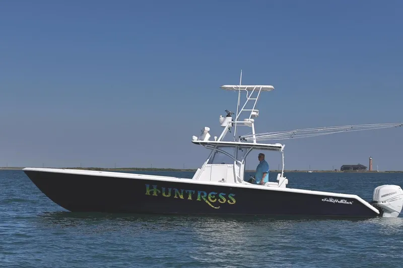 Slide: The Image of 2007 SeaHunter 40 boat named "Huntress" on calm water with clear sky. - 0