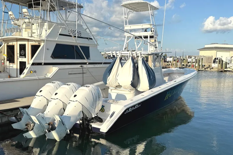Slide: The Image of 2007 SeaHunter 40 boat docked with triple outboard engines, clear sky background. - 16