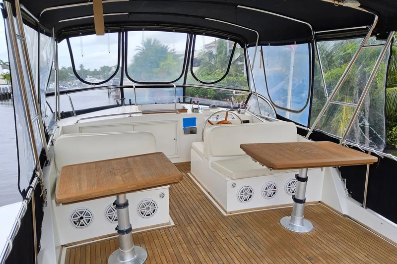 Slide: The Image of 1997 Grand Banks 46 Europa yacht interior with wooden tables and seating, featuring a covered deck. - 24