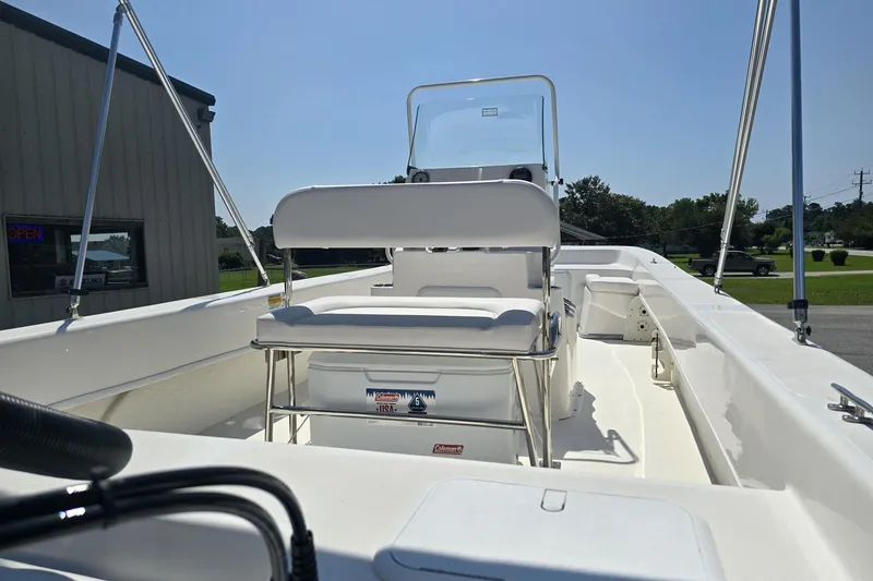 Slide: The Image of 2026 Sundance B22CCR boat interior with seating and console, parked outdoors. - 6