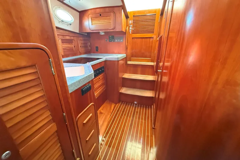 Slide: The Image of Interior of 2003 Hinckley Talaria 40 yacht with wooden cabinetry and compact kitchen area. - 13