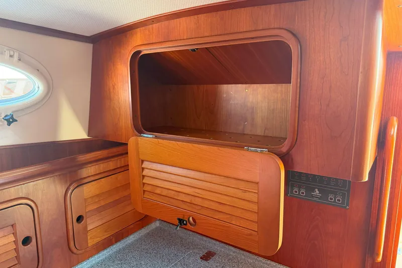 Slide: The Image of 2003 Hinckley Talaria 40 interior with wooden cabinetry and open storage compartment. - 16
