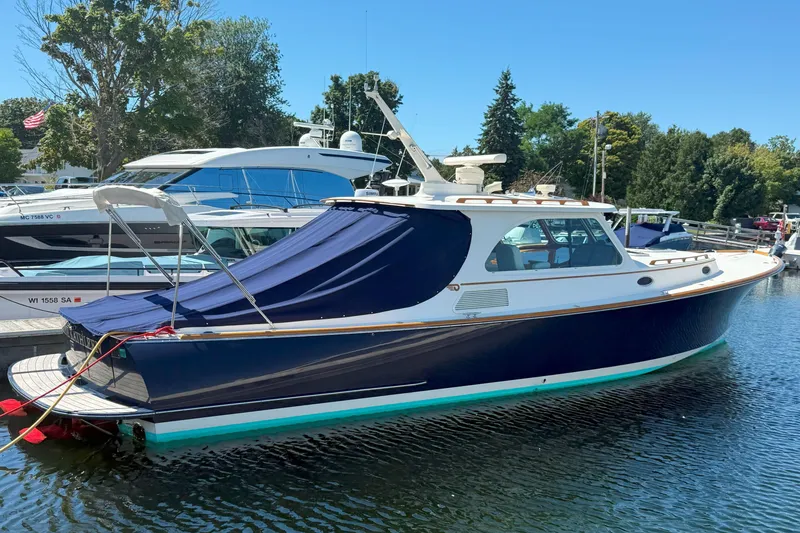 Slide: The Image of 2003 Hinckley Talaria 40 yacht docked, featuring a sleek blue hull and covered deck. - 21