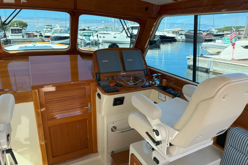 Slide: The Image of Helm of 2003 Hinckley Talaria 40 yacht with wooden accents and marina view. - 9