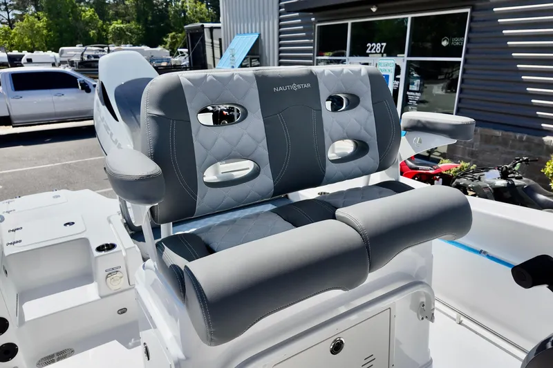 Slide: The Image of 2026 NauticStar 251 Hybrid boat seat with gray upholstery and armrests, displayed outdoors. - 17