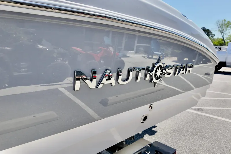 Slide: The Image of 2026 NauticStar 251 Hybrid boat logo on sleek hull in parking lot. - 23