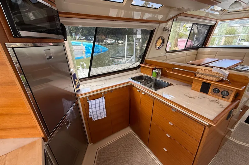 Slide: The Image of Luxurious 2021 Ranger Tugs R-41CB yacht kitchen with wood cabinetry and marina view. - 17