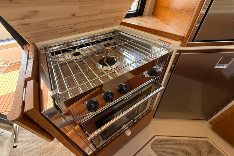 Slide: The Image of 2021 Ranger Tugs R-41CB yacht kitchen with stainless steel stove and wooden cabinetry. - 20