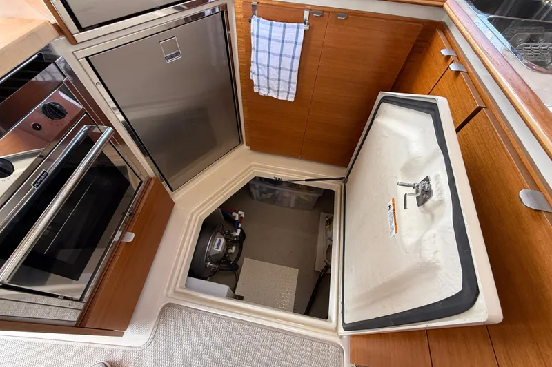 Slide: The Image of 2021 Ranger Tugs R-41CB galley with open engine compartment, stainless appliances, and wood cabinetry. - 22