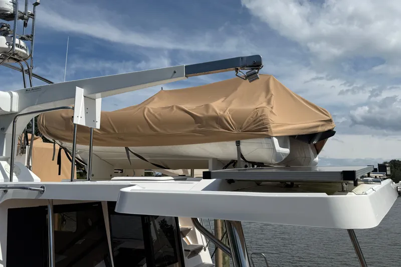 Slide: The Image of 2021 Ranger Tugs R-41CB with covered dinghy on deck under cloudy sky. - 54