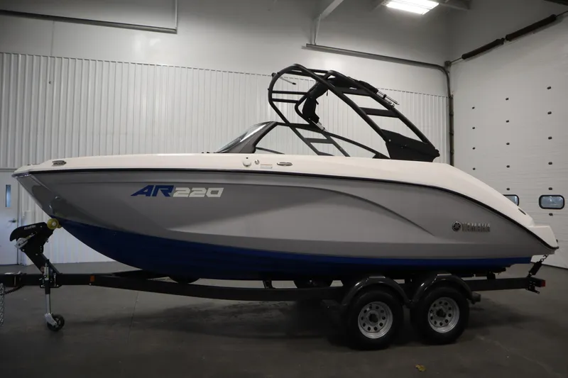 Slide: The Image of 2026 Yamaha Boats AR220 in a showroom, featuring sleek design and dual-axle trailer. - 7