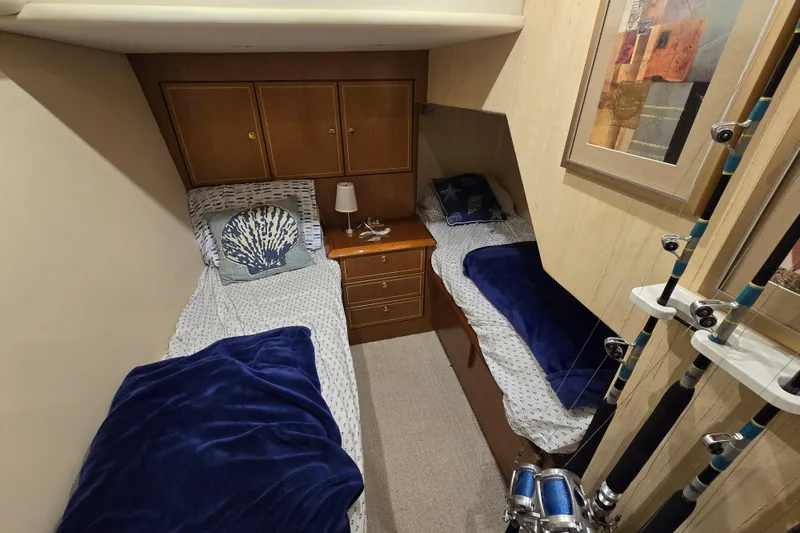 Slide: The Image of 2004 Ocean Yachts 50 Super Sport cabin with twin beds, blue blankets, and fishing rods. - 25