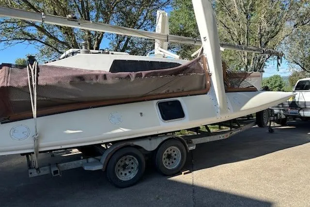 Slide: The Image of 1991 Corsair F-27 #227 sailboat on trailer, parked outdoors with trees in background. - 2