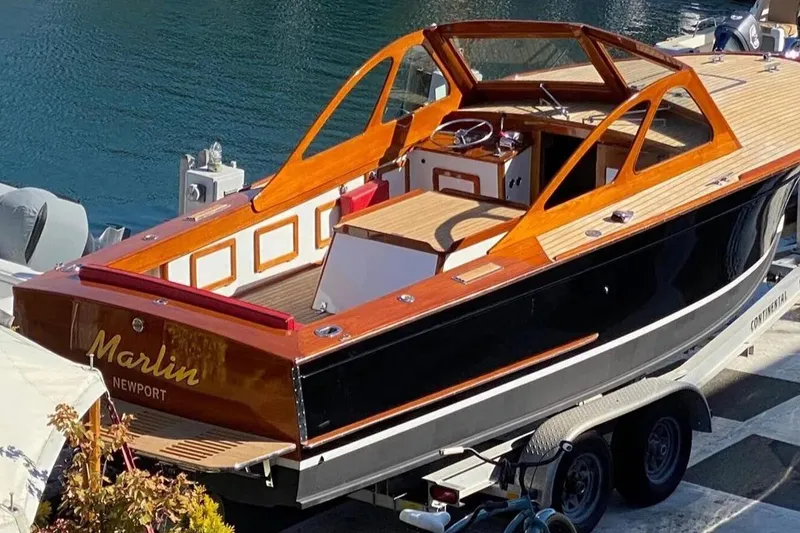 Slide: The Image of 1959 Forest E Johnson Prowler boat with wooden deck, docked by the water. - 10