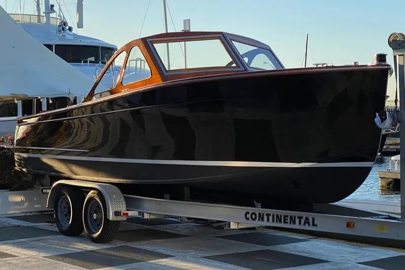 Slide: The Image of 1959 Forest E Johnson Prowler boat on trailer at marina, showcasing sleek black design. - 11
