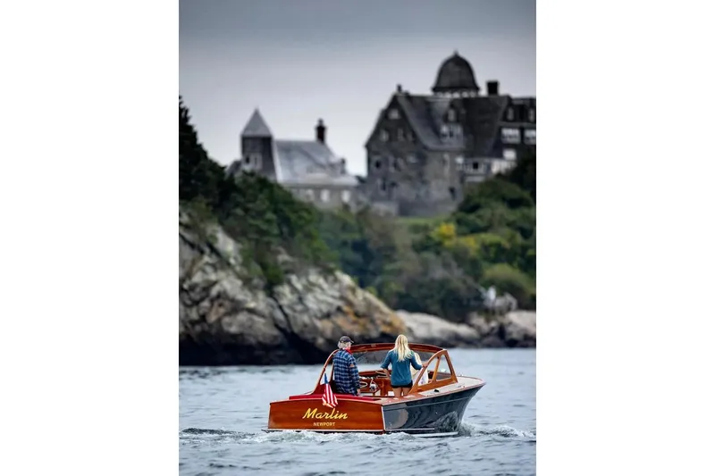 Slide: The Image of 1959 Forest E Johnson Prowler boat cruising near a historic stone mansion. - 12