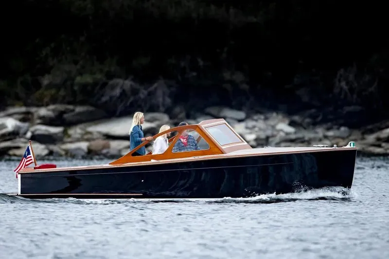 Slide: The Image of 1959 Forest E Johnson Prowler boat cruising on water with passengers, American flag displayed. - 4