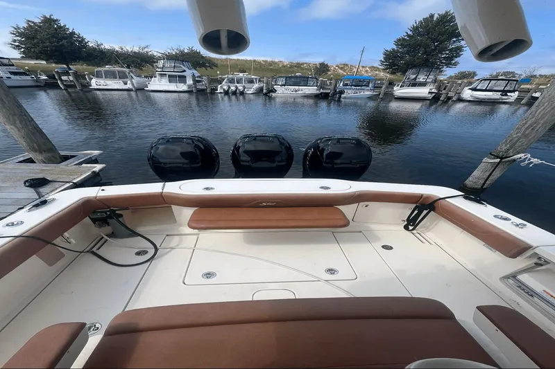 Slide: The Image of 2017 Scout 350 LXF boat docked, featuring triple outboard engines and spacious seating. - 8