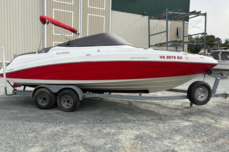 The Image of 2009 Yamaha Boats SX230 HO on trailer, red and white design, parked outdoors. - 1