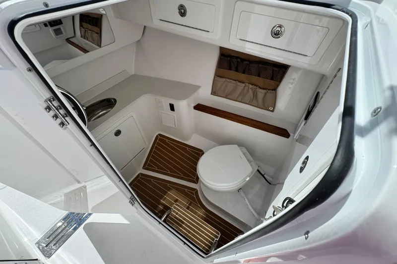 Slide: The Image of 2026 Southport 33 DC boat interior with compact bathroom, featuring a toilet and sink. - 16