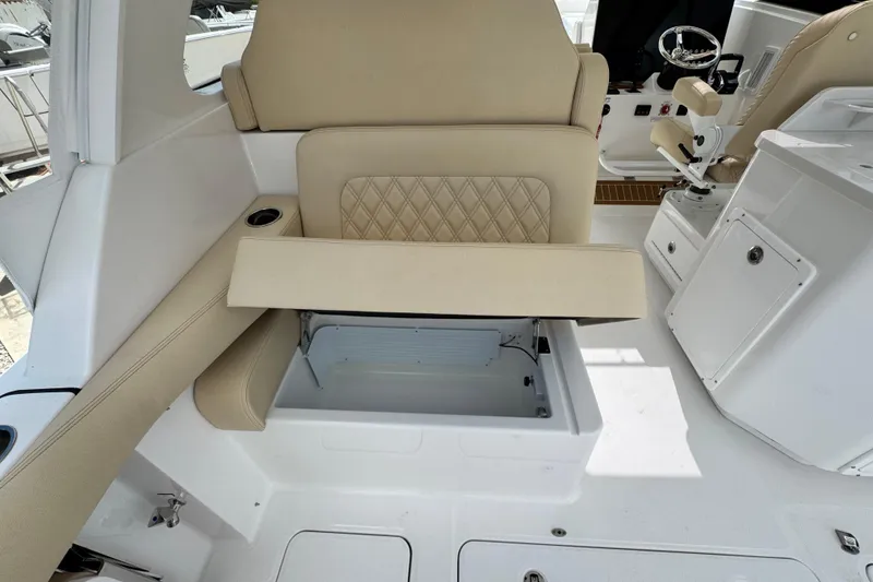 Slide: The Image of 2026 Southport 33 DC boat interior with beige seating and storage compartment open. - 33