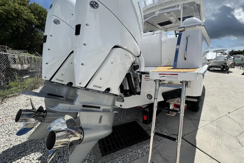 Slide: The Image of 2026 Southport 33 DC boat with dual outboard engines and ladder, parked on gravel. - 5