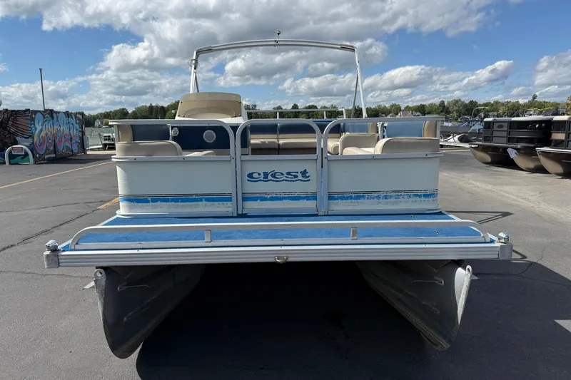 Slide: The Image of 1997 Crest 18 pontoon boat parked on asphalt under a cloudy sky. - 2