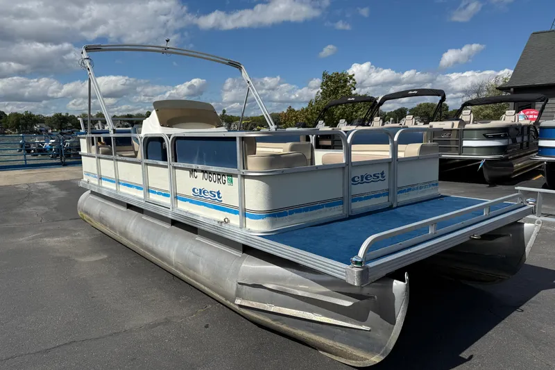 Slide: The Image of 1997 Crest 18 pontoon boat with blue carpet, docked under a partly cloudy sky. - 3
