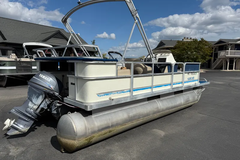 Slide: The Image of 1997 Crest 18 pontoon boat with Yamaha outboard motor, parked outdoors. - 4