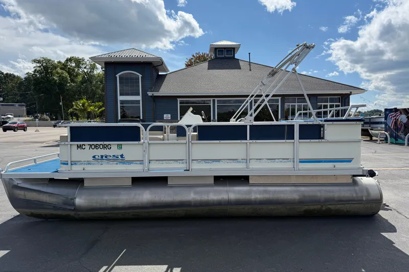 Slide: The Image of 1997 Crest 18 pontoon boat parked in front of a building under a partly cloudy sky. - 7