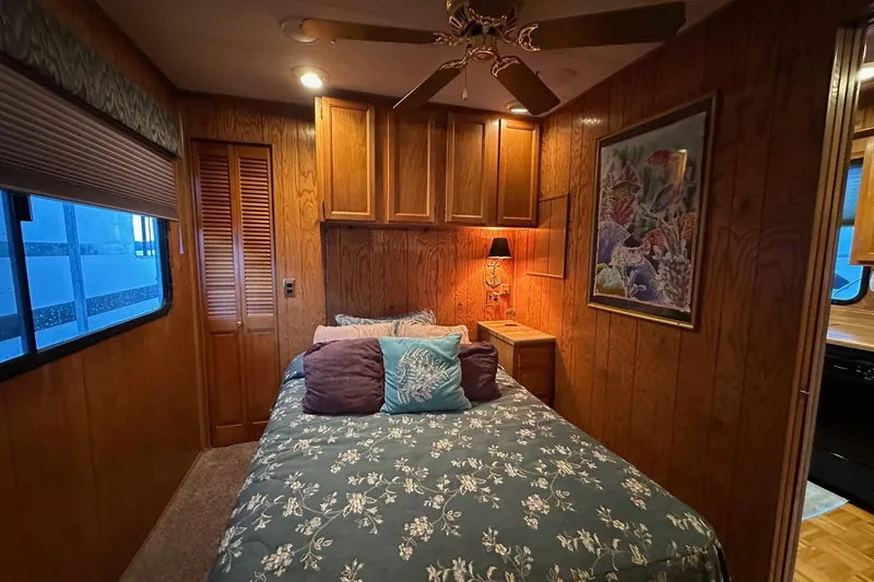Slide: The Image of 1989 Sumerset 14x71 houseboat interior with wood paneling, glass table, and stained glass cabinet. - 6