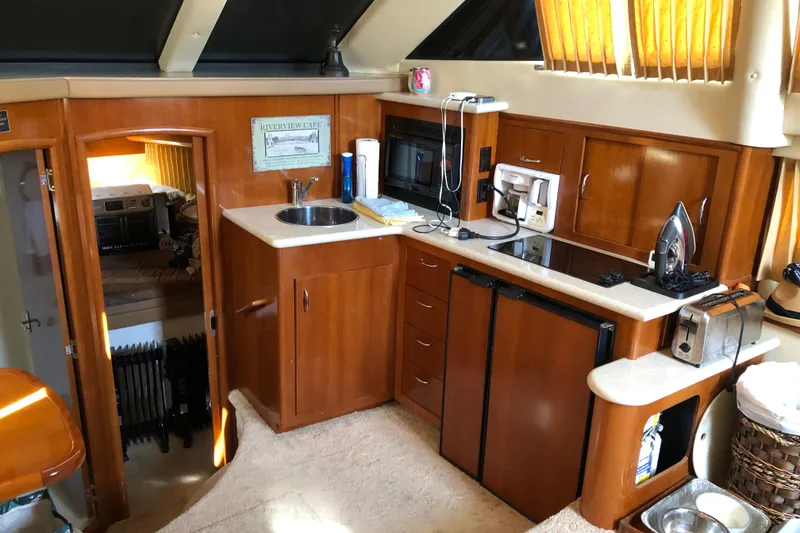 Slide: The Image of 2004 Carver 366 Motor Yacht interior with kitchenette, featuring wood cabinetry and modern appliances. - 6