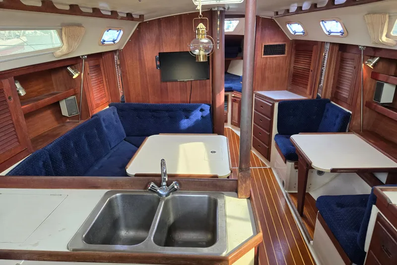 Slide: The Image of Interior of 1989 Catalina 36 sailboat with wood finish, blue seating, and kitchenette. - 11
