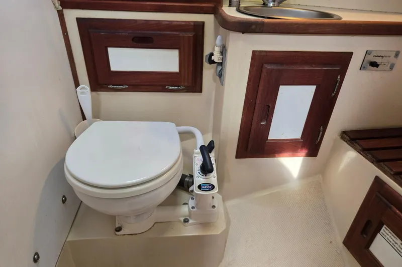 Slide: The Image of 1989 Catalina 36 yacht bathroom with toilet, sink, and wooden cabinetry. - 26