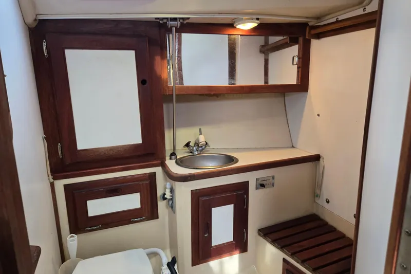 Slide: The Image of 1989 Catalina 36 yacht bathroom with wooden cabinets, sink, and mirror. - 27