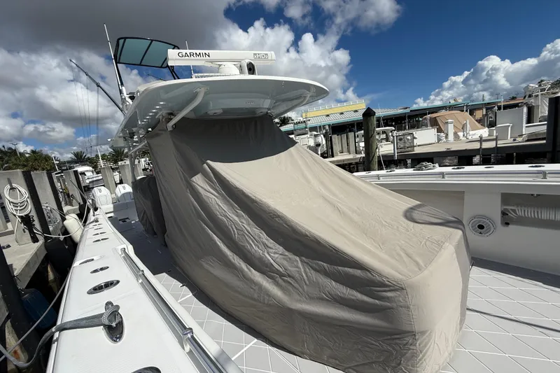 Slide: The Image of 2022 Invincible 46 Catamaran docked, covered, with Garmin equipment, under a partly cloudy sky. - 71