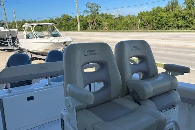Slide: The Image of 2018 Cobia 277 Center Console boat seats with dual engines in a sunny outdoor setting. - 6