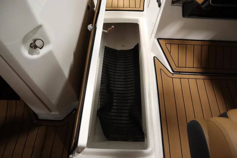 Slide: The Image of Open storage compartment on 2026 Yamaha Boats 252SD with teak-style flooring. - 28