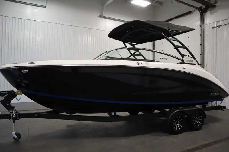 Slide: The Image of 2026 Yamaha Boats 252SD in showroom, sleek black and white design, on trailer. - 7