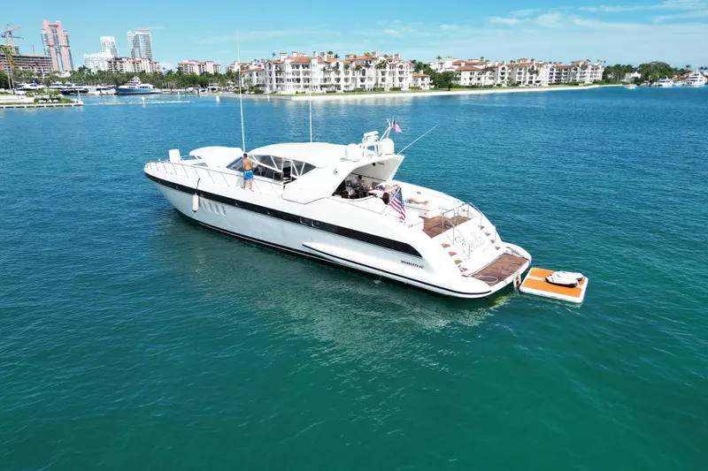 Slide: The Image of 1999 Mangusta 80 yacht cruising in clear blue waters near luxury waterfront residences. - 11