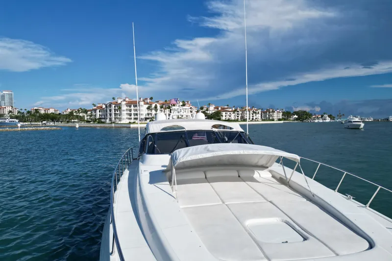 Slide: The Image of 1999 Mangusta 80 yacht cruising near luxury waterfront residences under a clear blue sky. - 15