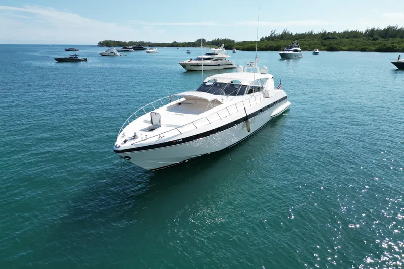 Slide: The Image of 1999 Mangusta 80 yacht anchored in a serene bay with other boats. - 2