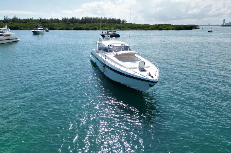 Slide: The Image of 1999 Mangusta 80 yacht anchored in clear blue water, surrounded by other boats. - 4