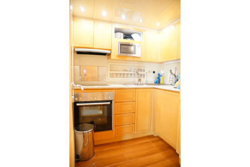 Slide: The Image of Compact kitchen in a 1999 Mangusta 80 yacht with wooden cabinets and modern appliances. - 40